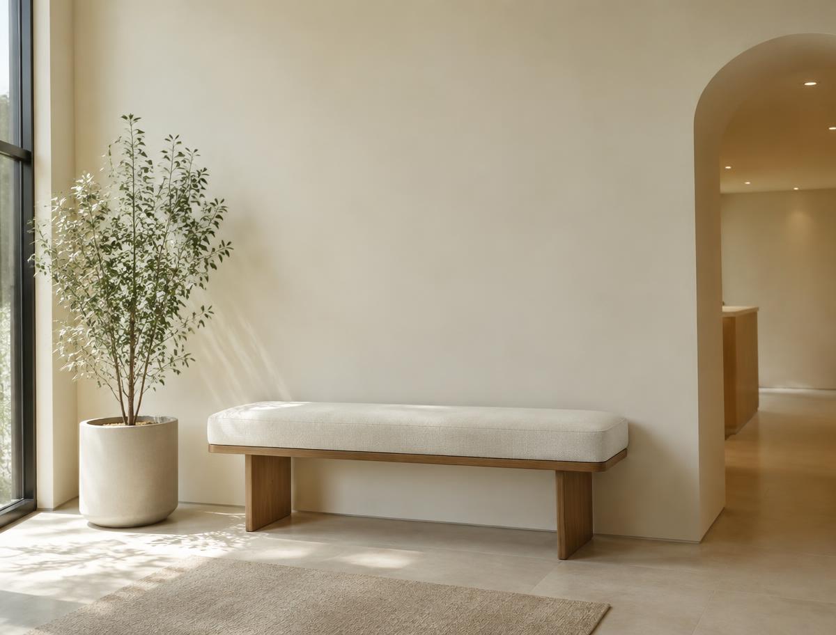 Quiet waiting area with a linen bench, plant and soft daylight